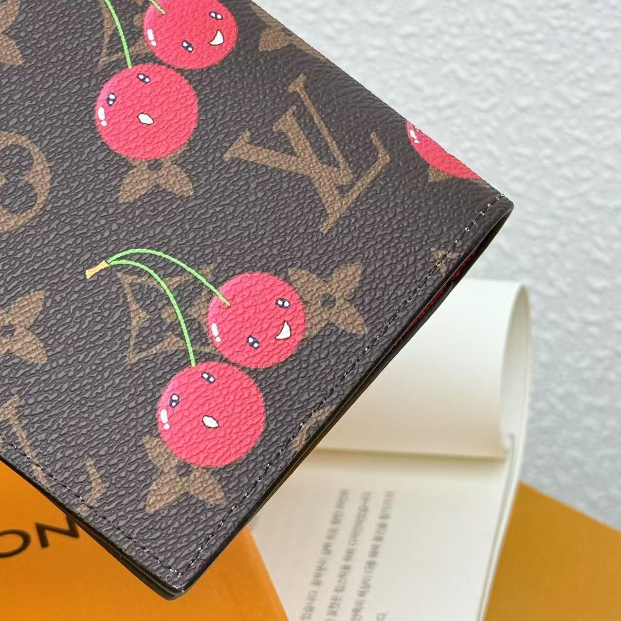 Louis Vuitton wallet with cherry design on a textured surface